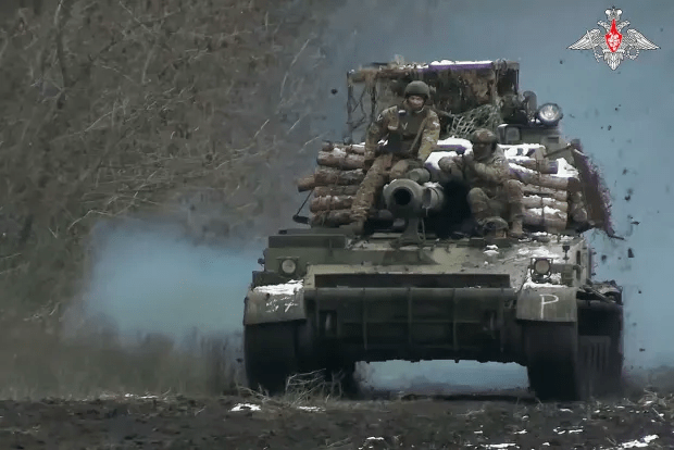 Military vehicle moving through a wooded area.