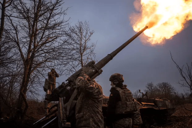 Soldiers firing a howitzer.