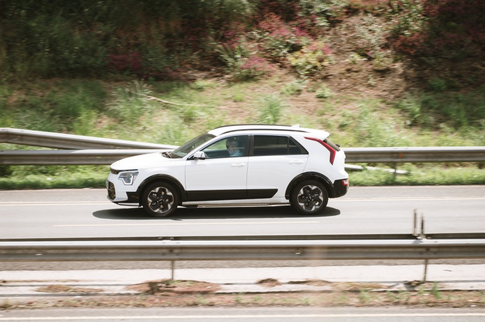 White Kia Niro driving on a highway.
