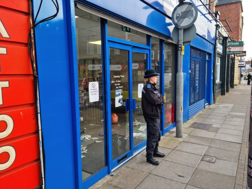 Police officer standing outside a shop after a stabbing.