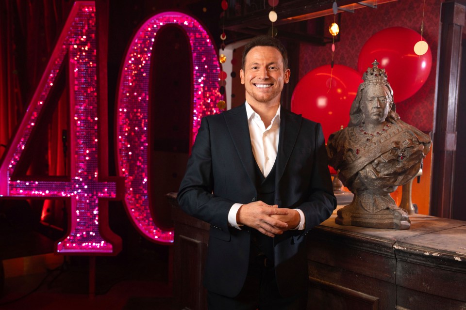 Joe Swash standing in front of a number 40 made of pink sequins.