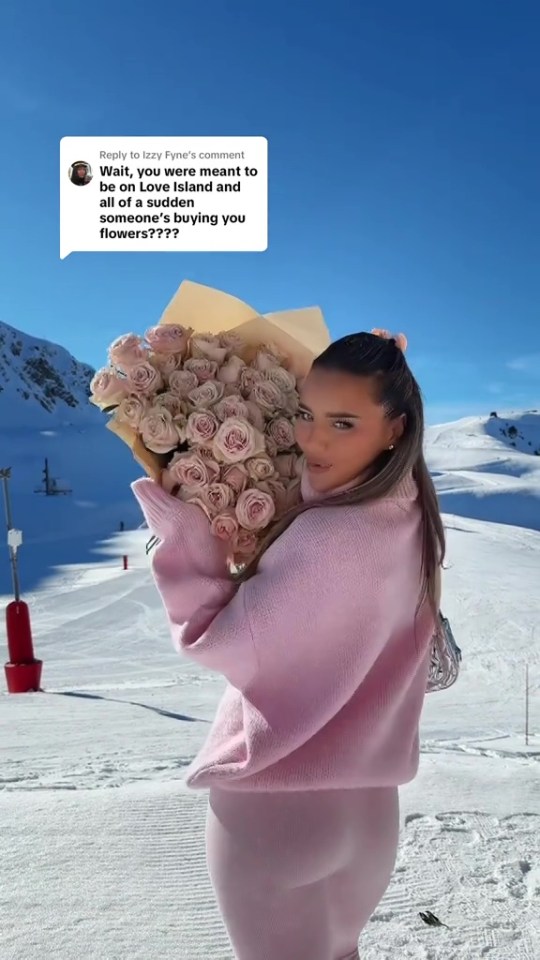 Lucinda Strafford holding a bouquet of pink roses in a snowy landscape.