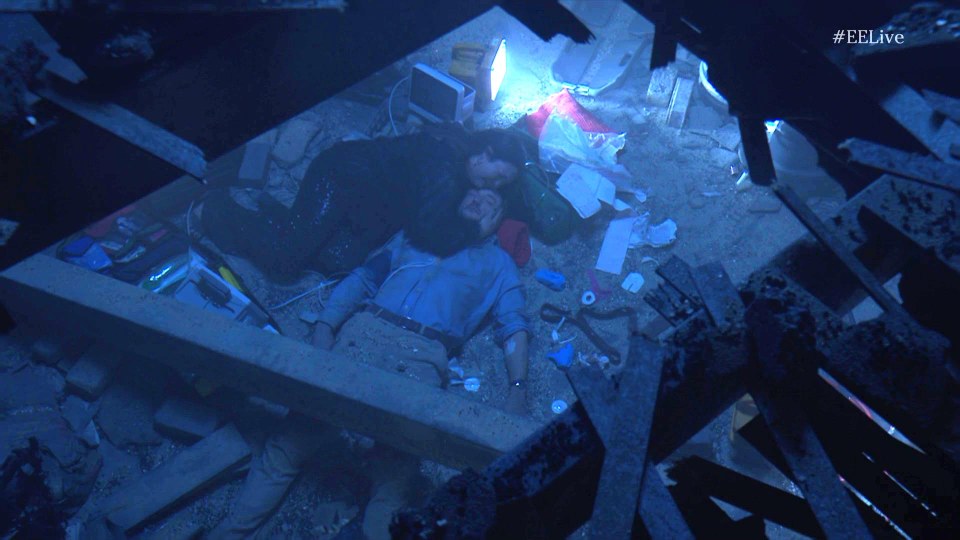 Martin Fowler injured and being comforted amidst rubble.