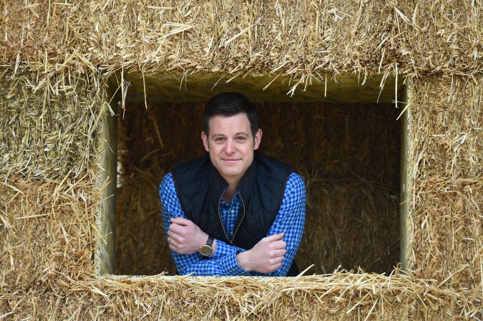 Group photo of Countryfile presenters with lambs and a dog, surrounded by hay bales.