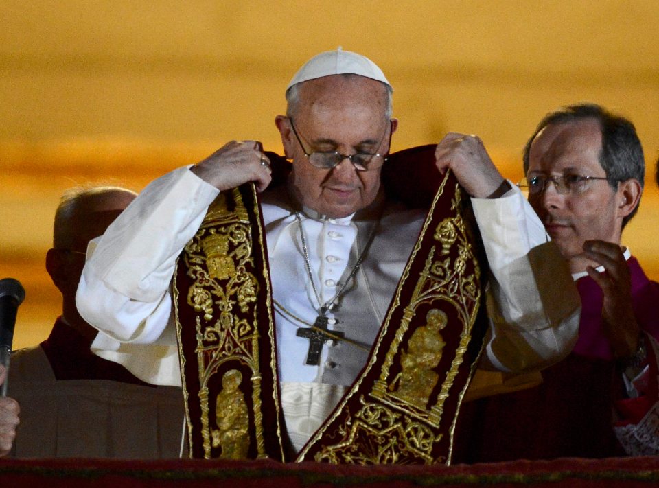Pope Francis adjusting his stole on the balcony of St. Peter's Basilica.