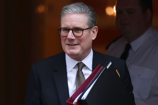 A man in a suit and glasses carrying files.