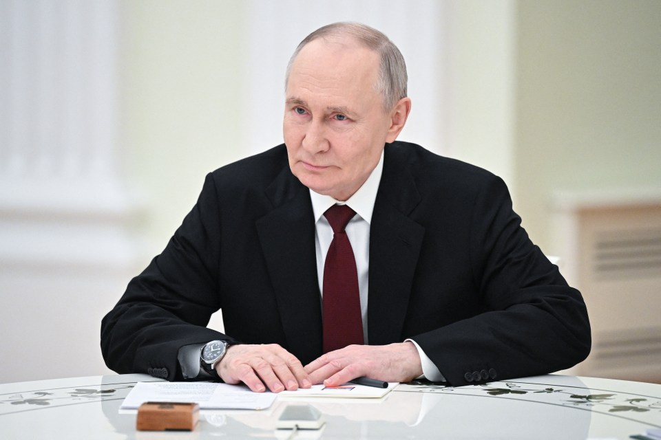 Vladimir Putin sitting at a table.