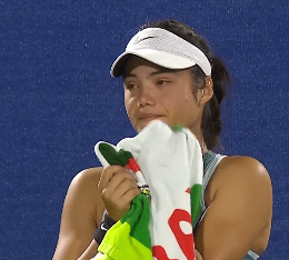 A female tennis player crying and holding a towel.