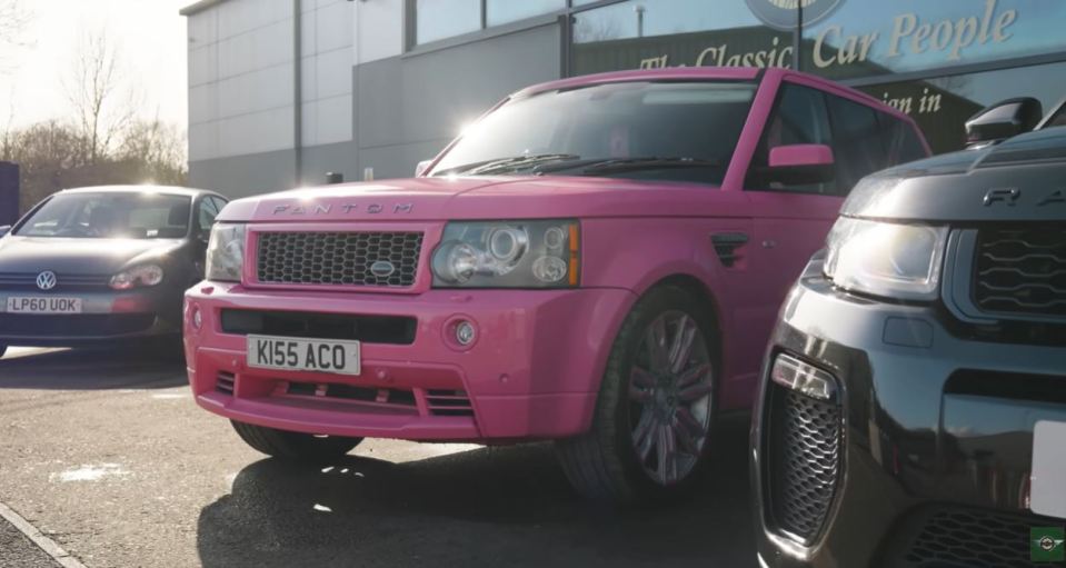 Pink Range Rover parked in front of a car dealership.