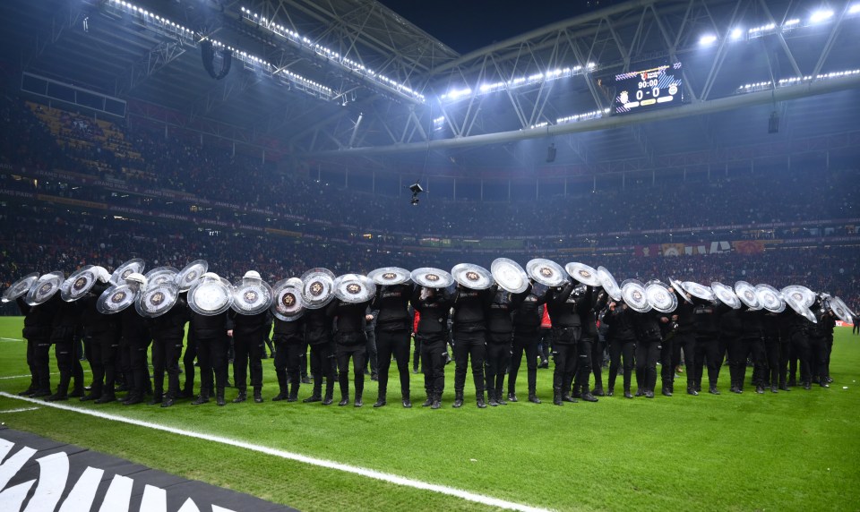 Police officers with shields at a soccer game.