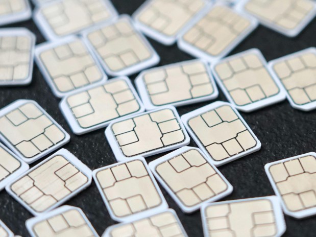 Many SIM cards scattered on a dark surface.