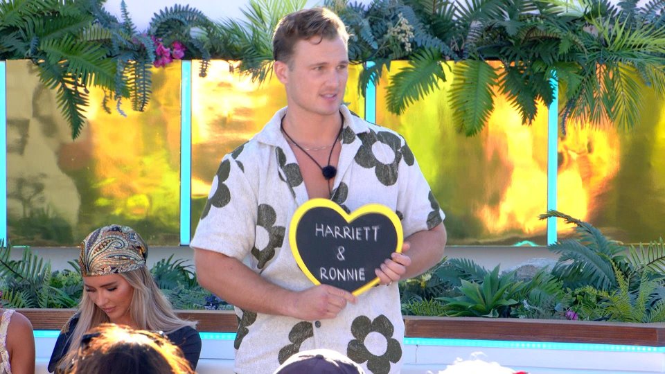 Chuggs Wallis from Love Island: All Stars holding a sign that says "Harriett & Ronnie".