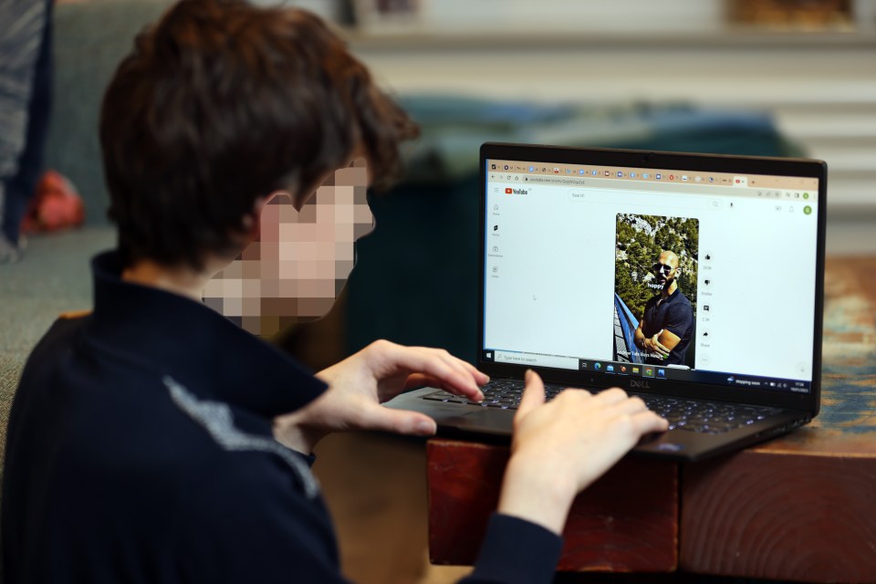 Person viewing a YouTube video of Andrew Tate on a laptop.