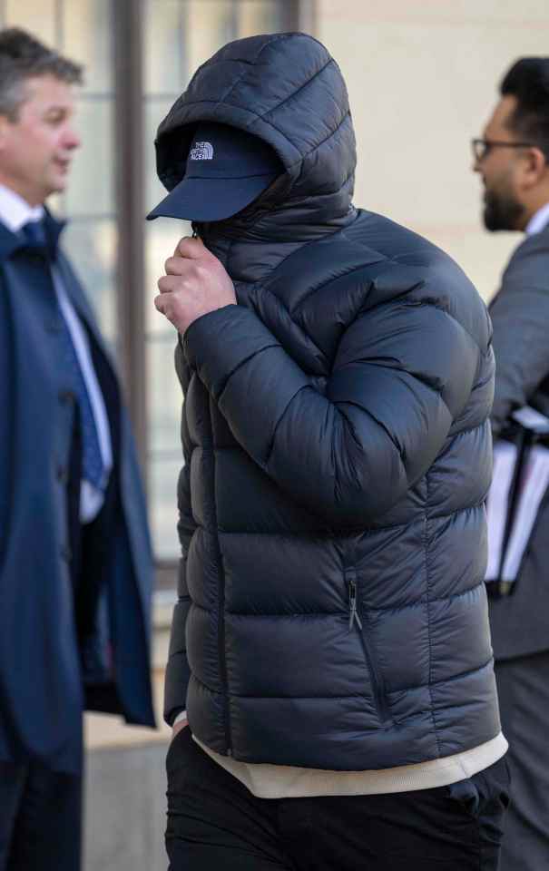 A man in a hooded jacket and baseball cap at a court hearing.