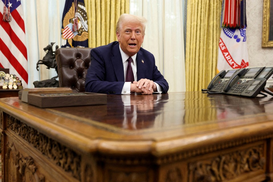 President Donald Trump sitting at the Resolute Desk in the Oval Office.