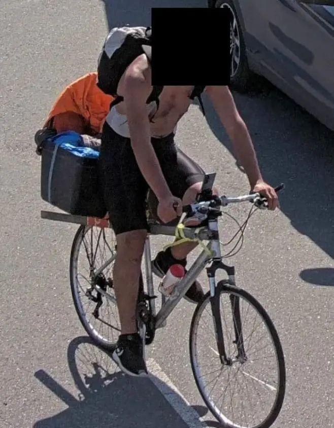 Man riding a bicycle with luggage attached.