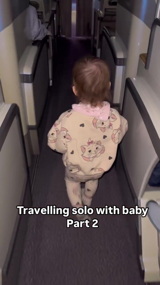Toddler walking down airplane aisle.
