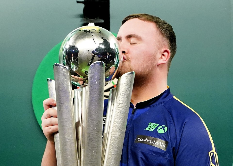 Luke Littler kissing the Sid Waddell Trophy.