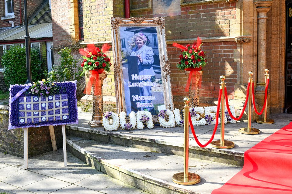 Funeral arrangements for Doreen Bawn, including floral tributes and a framed photo.