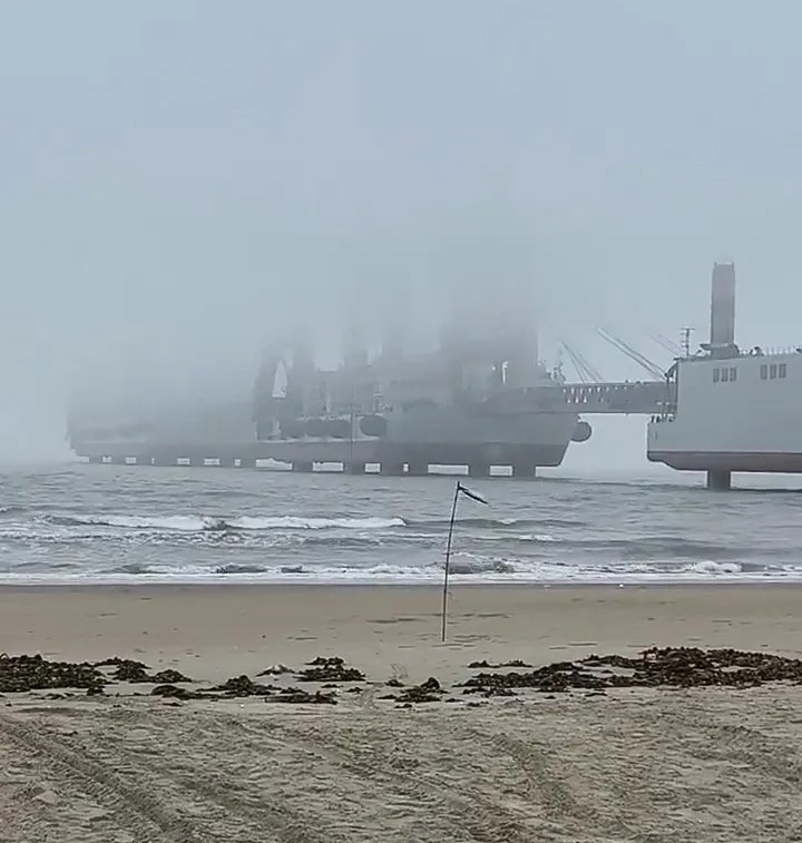 Large barges off the coast in foggy conditions.