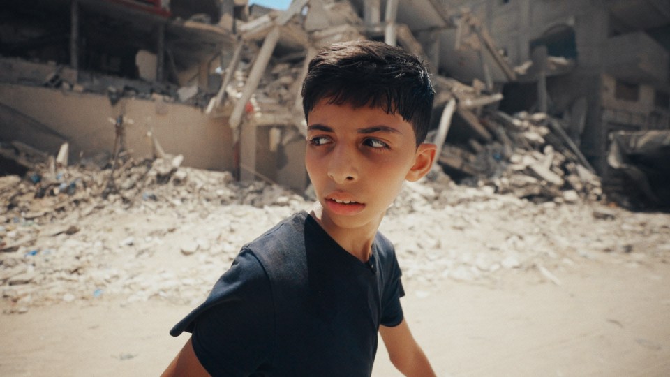 Boy looking over his shoulder in war-torn area.