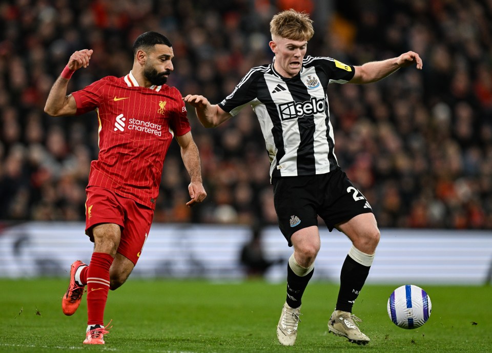 Mohamed Salah of Liverpool and Lewis Hall of Newcastle United competing for the ball during a soccer match.