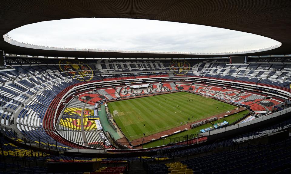 Estadio Azteca during a football game with the Mexican and American flags displayed on the field.
