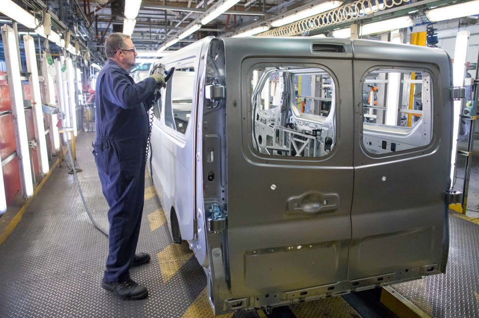 Factory worker smoothing the edges of a van body panel.