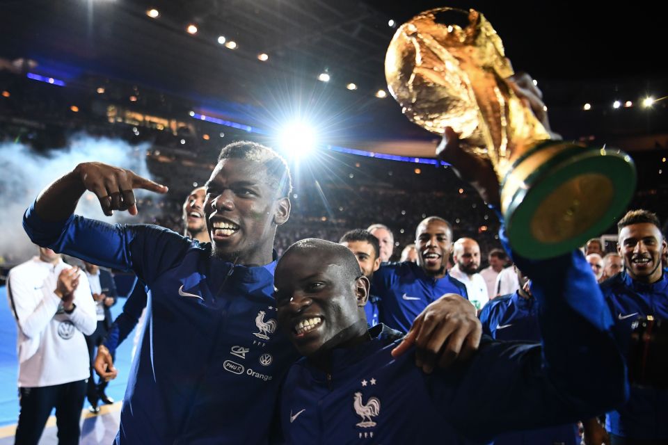 Paul Pogba and N'Golo Kanté holding the 2018 World Cup trophy.