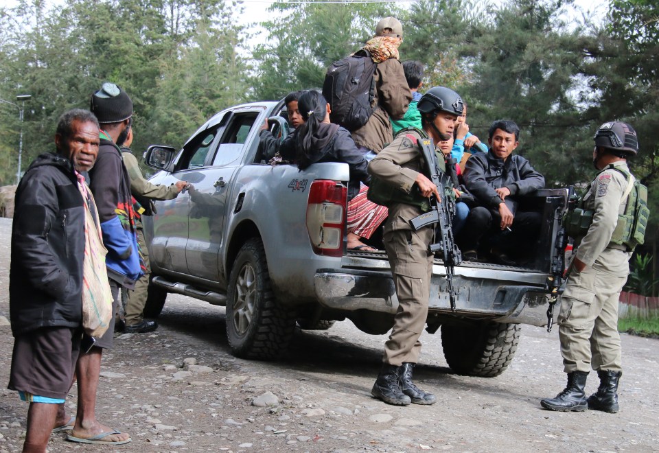 Indonesian police securing the evacuation of residents following arson and shootings.