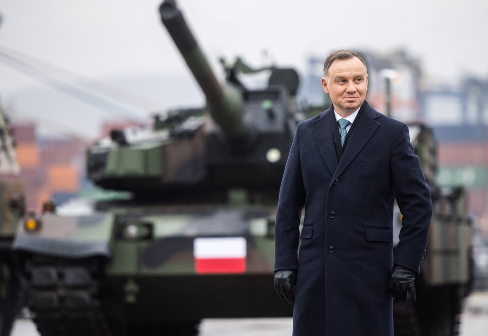 President Andrzej Duda standing in front of Polish military tanks.