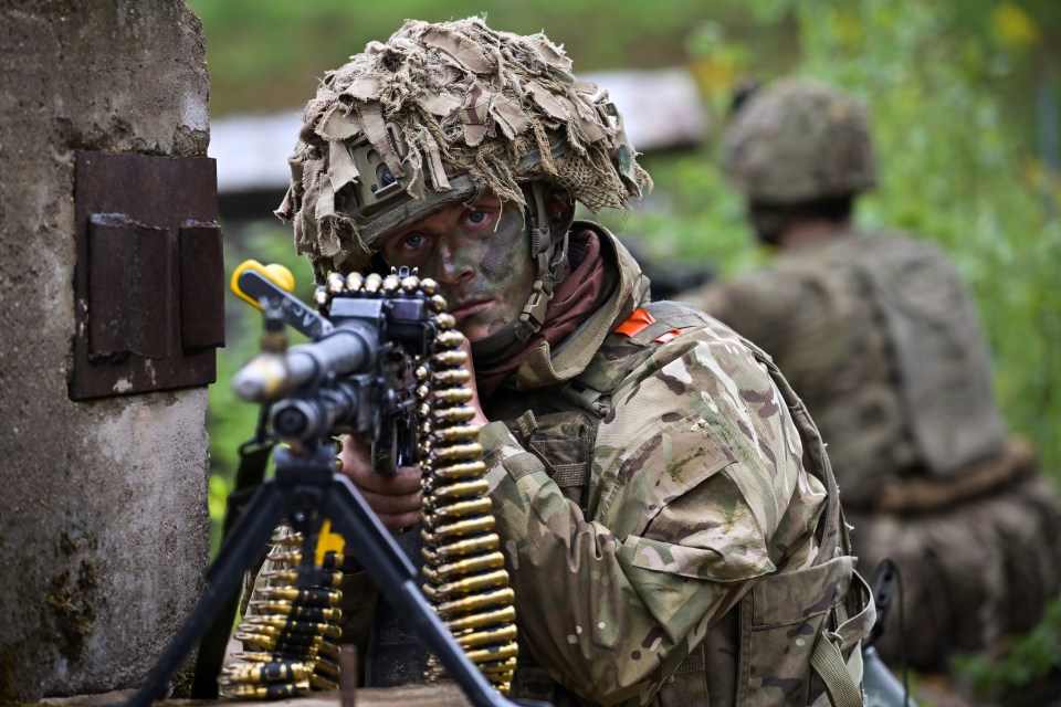 Soldier aiming a machine gun during a military exercise.