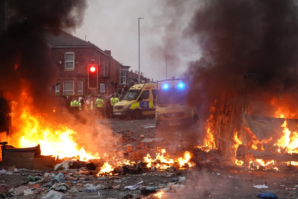 Riot police and burning vehicles during a protest.