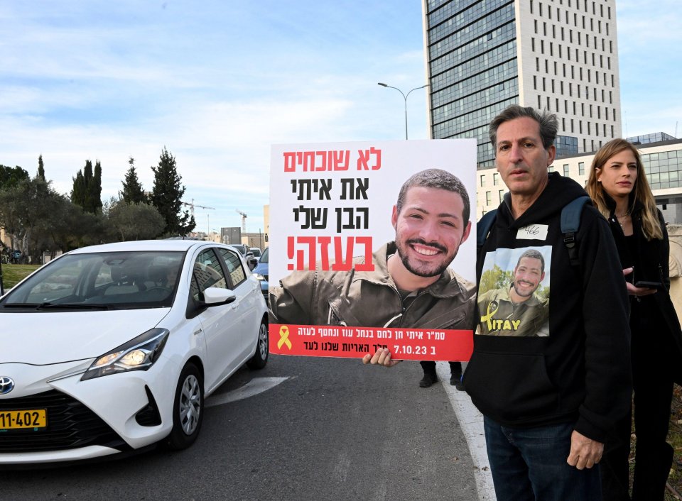 Protestor holding a sign with a photo of his son, who was killed and is being held hostage.