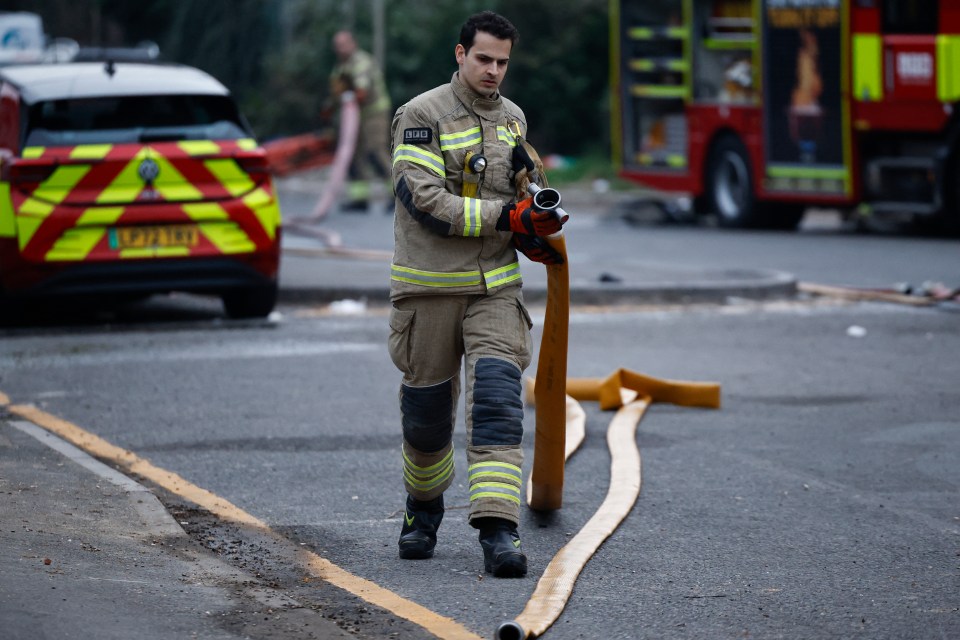 Firefighter carrying a fire hose at Heathrow Airport.