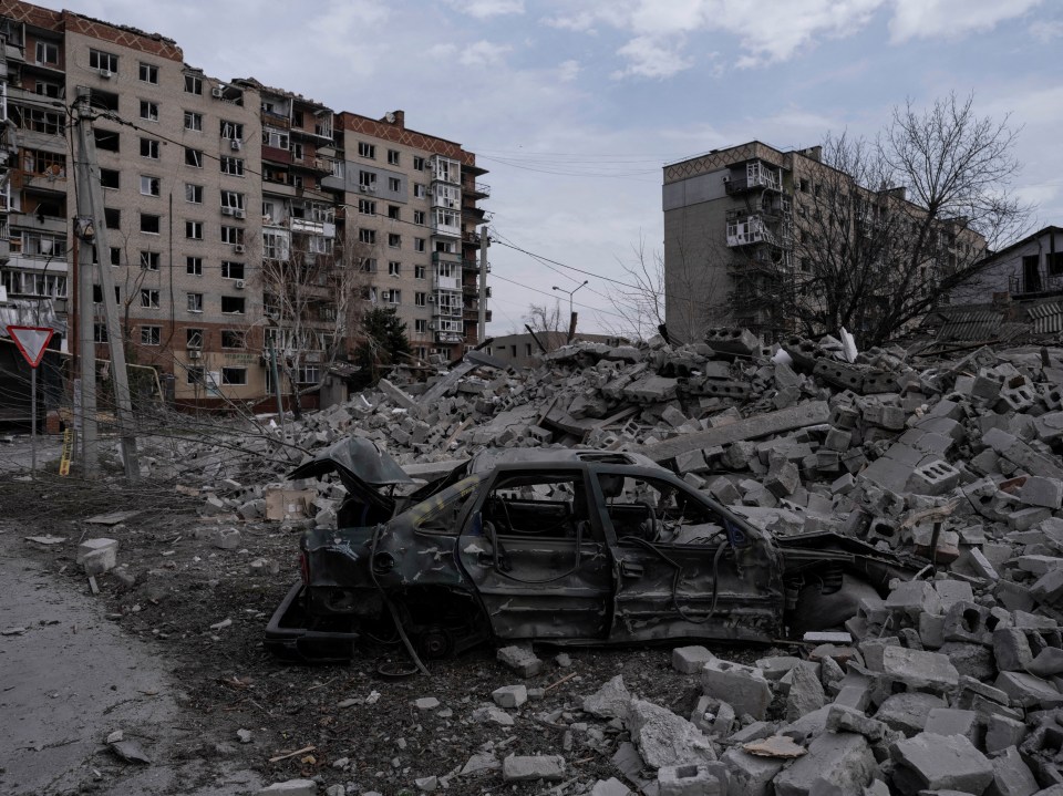 Damaged car amidst rubble and destroyed buildings.