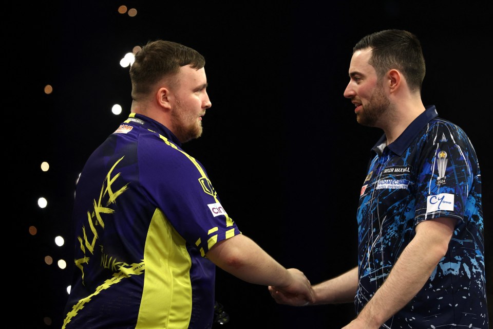 Luke Littler and Luke Humphries shaking hands at a darts match.