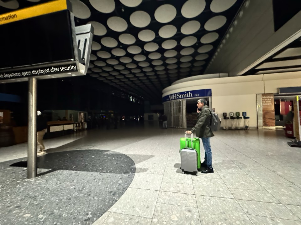 A passenger with luggage in a dark Heathrow Airport terminal.