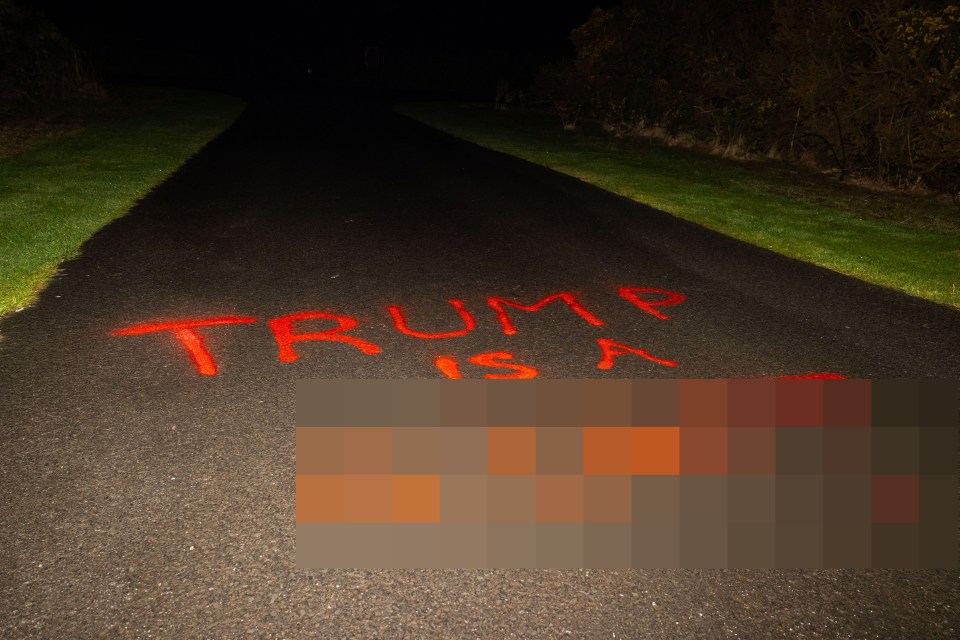 Graffiti on a road reads "Trump is a c***."