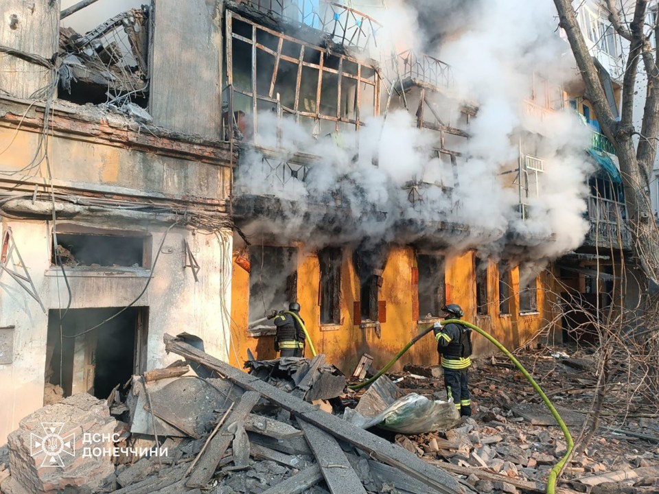 Rescuers battling a fire at a damaged building.
