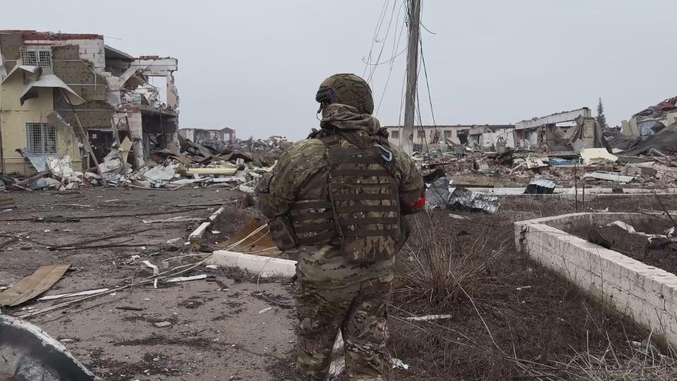 A Russian soldier in a war-torn settlement.