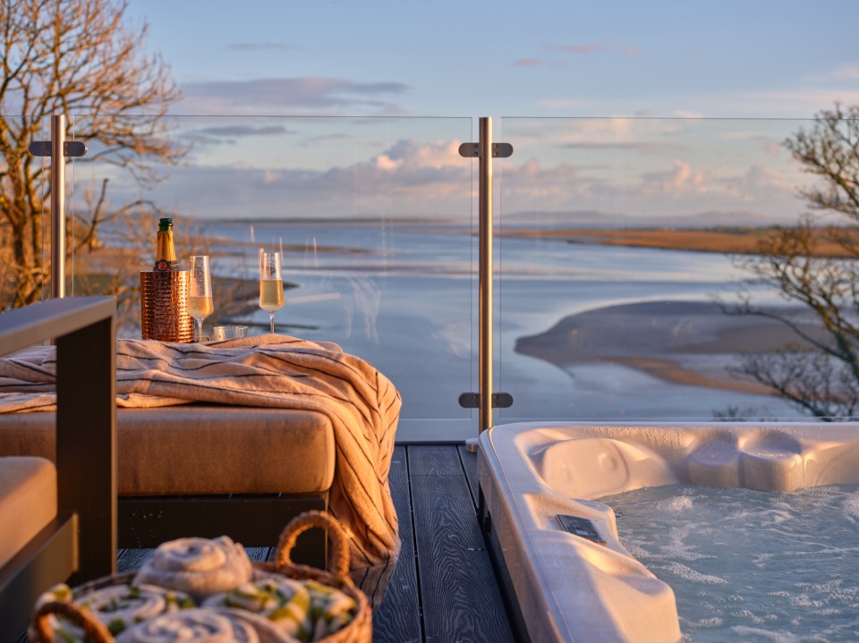 Hot tub and champagne on a deck overlooking a river at sunset.
