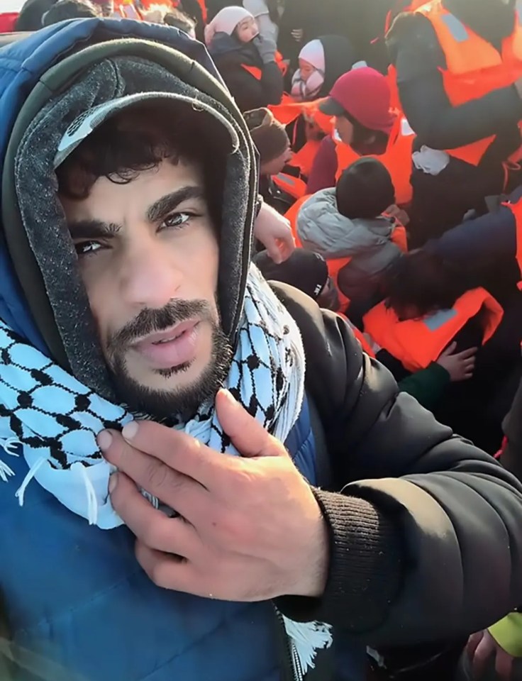 A man in a keffiyeh and lifejacket on a crowded migrant boat.