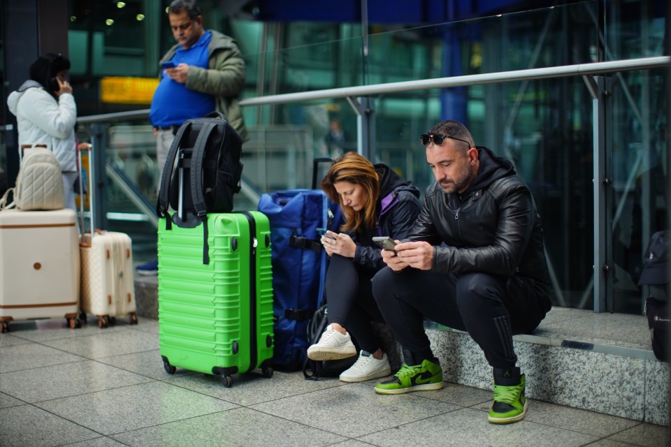 Stranded passengers at Heathrow Airport using their phones.
