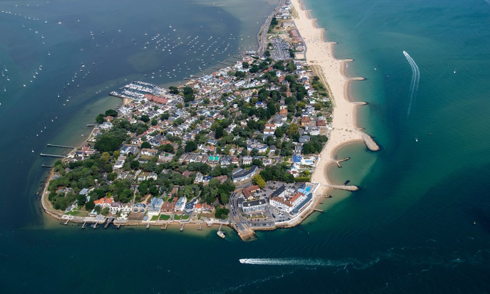 Aerial view of Sandbanks peninsula in Poole, Dorset, showing houses, beach, and boats.
