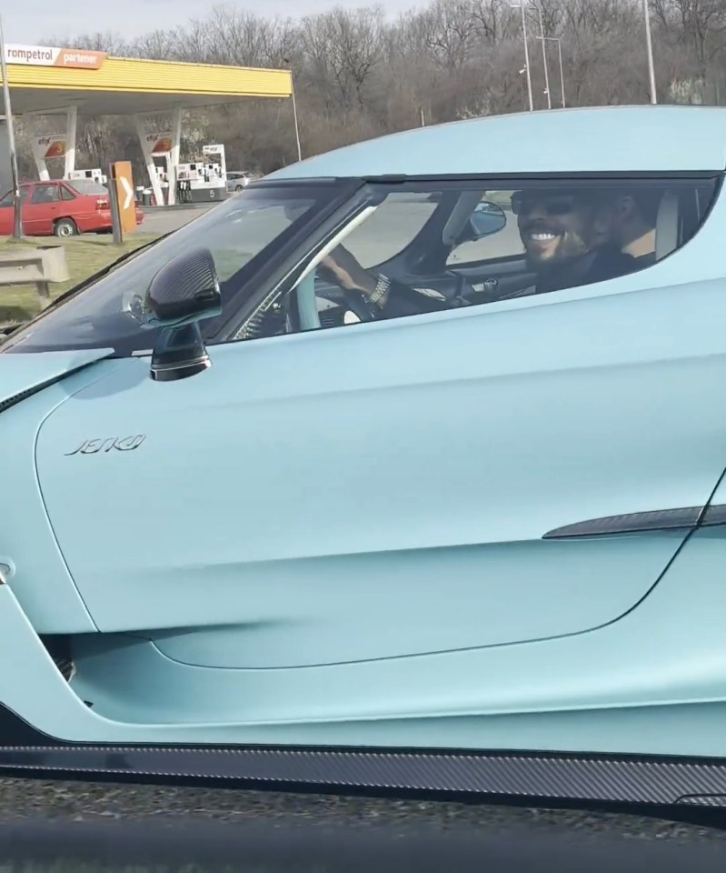 Andrew Tate driving a light blue Koenigsegg Jesko.