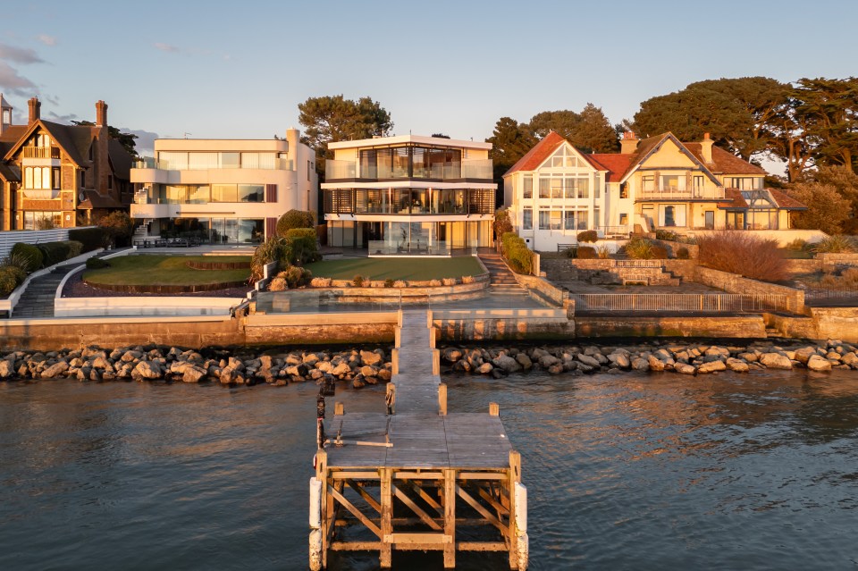 Waterfront mansion and adjacent houses with a wooden pier.