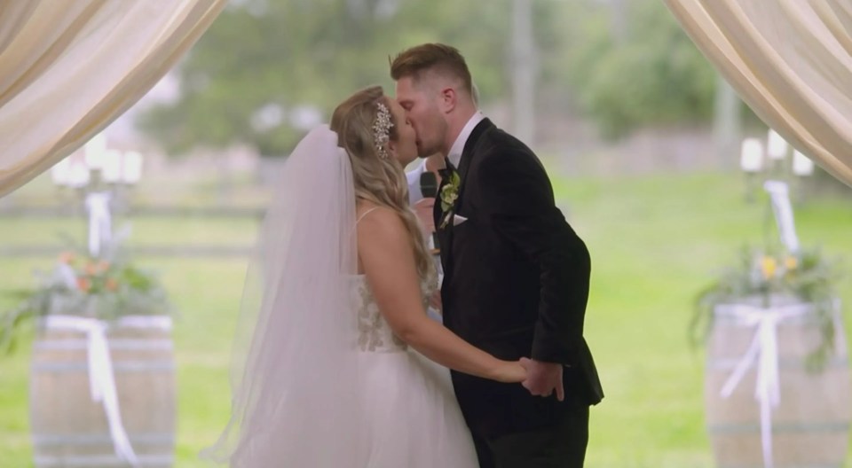 A bride and groom kissing at their wedding ceremony.