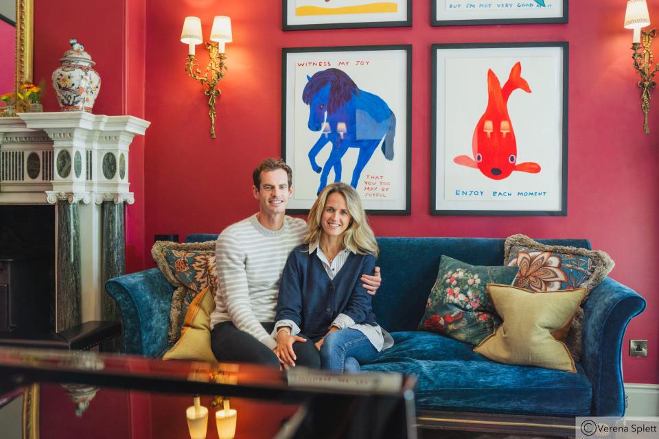 Couple sitting on a blue velvet sofa in a room with colorful artwork.