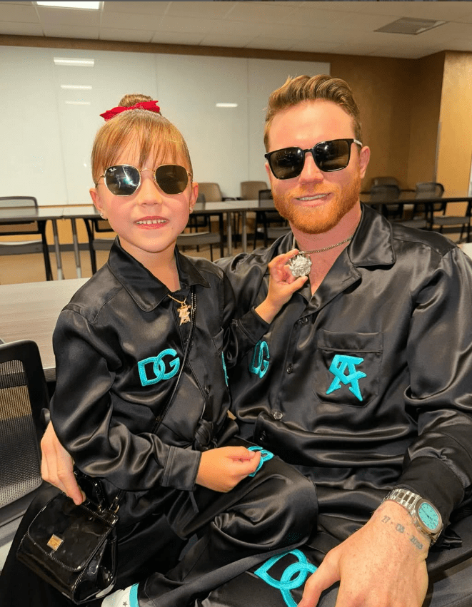 A father and daughter wearing matching black Dolce & Gabbana outfits.